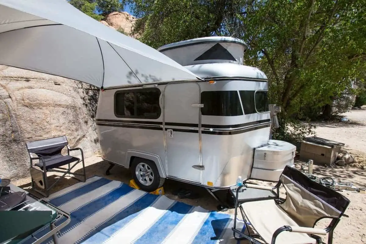 tiny rv set up with awning and rug
